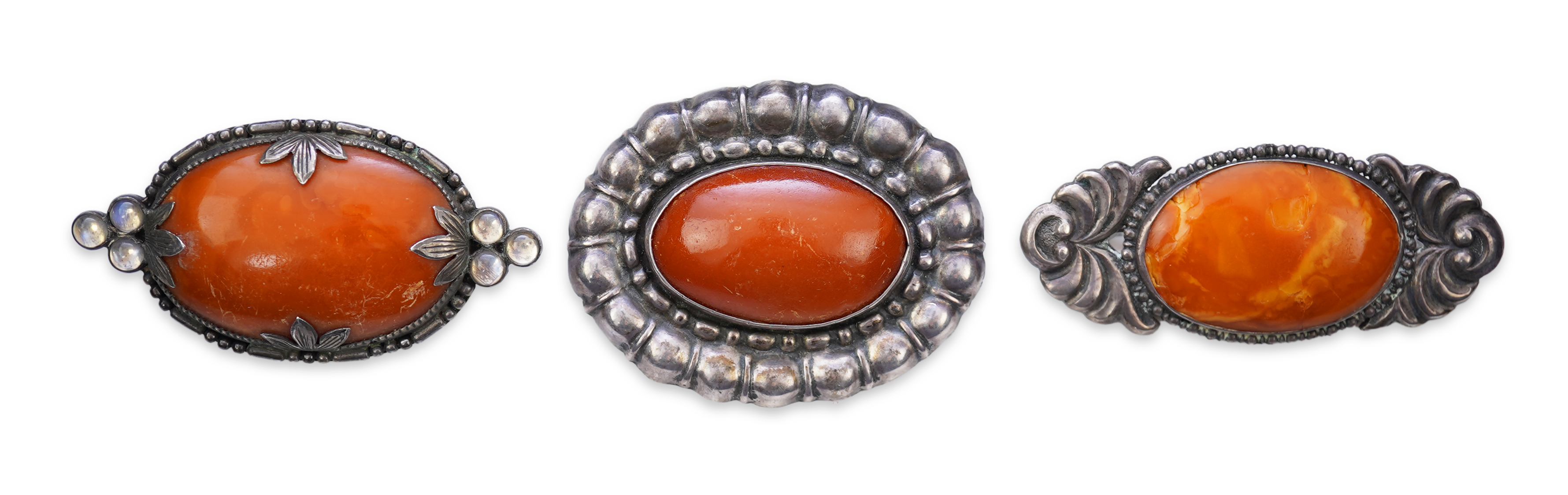 Three Arts & Crafts silver and amber brooches, early 20th century